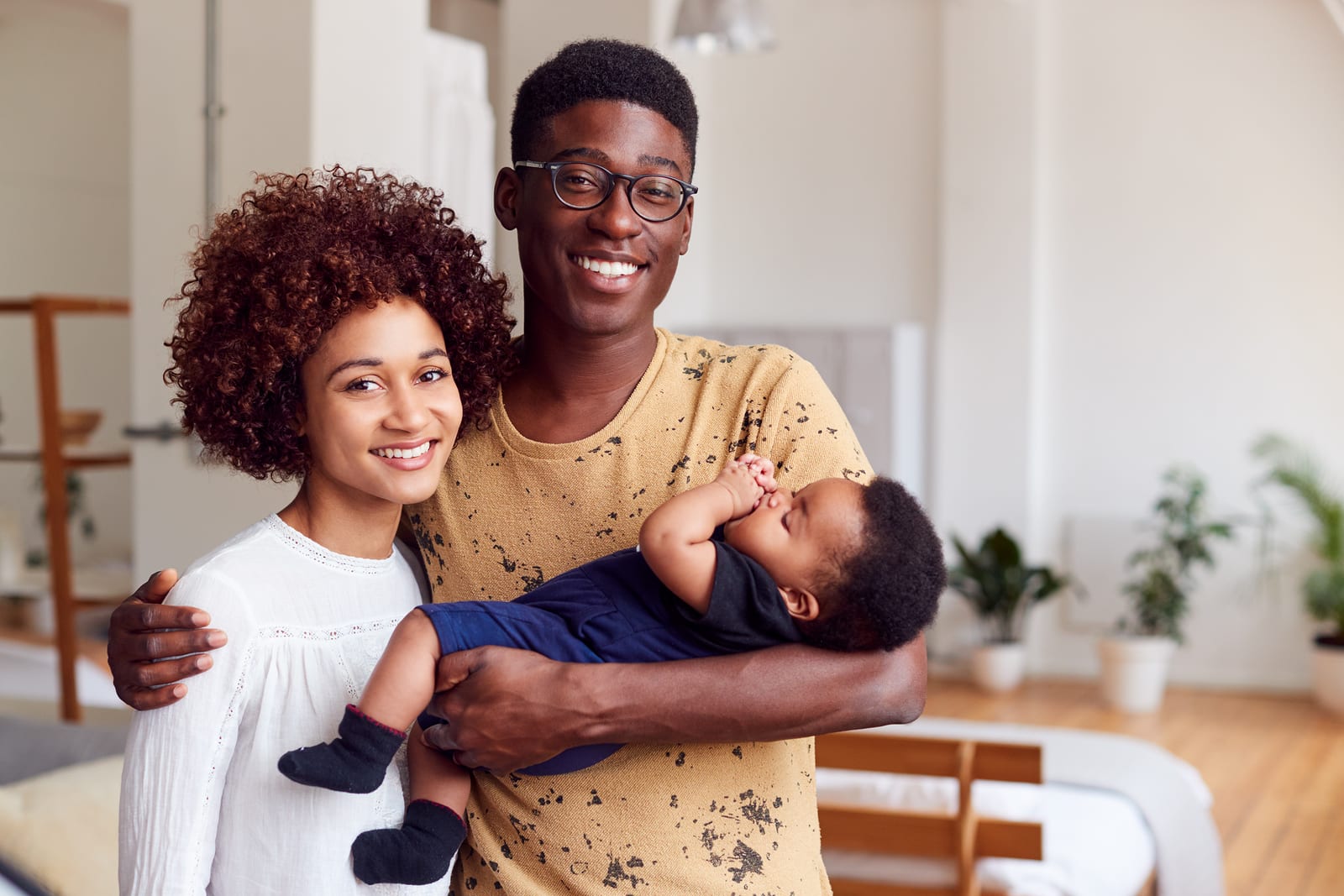 Portrait Of Loving Parents Holding Newborn Baby At Home In Loft