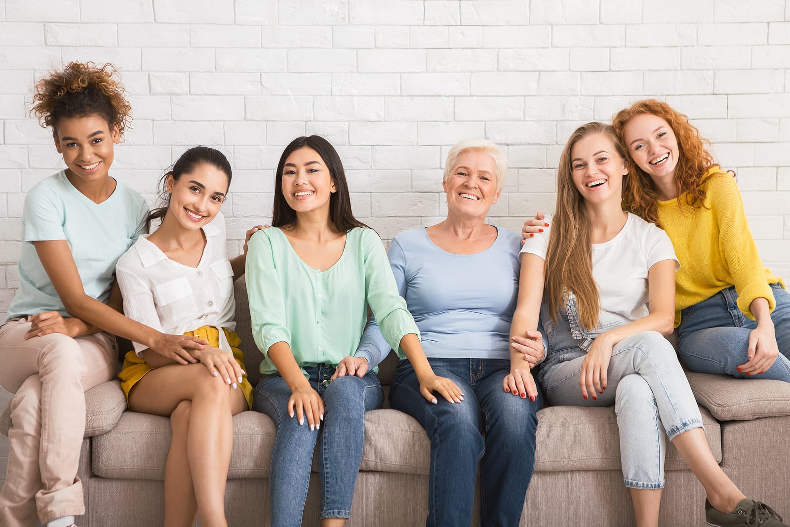 Group Of Diverse Women Smiling At Camera Sitting On Couch Agains